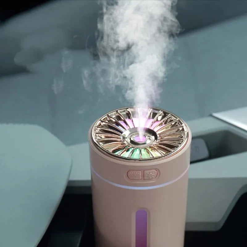 Black wireless ultrasonic humidifier with colourful lights, shown next to a USB cable on a desk.