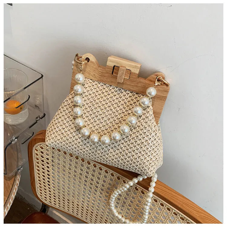 Women's straw woven shoulder bag with pearl chain trim showing internal compartments