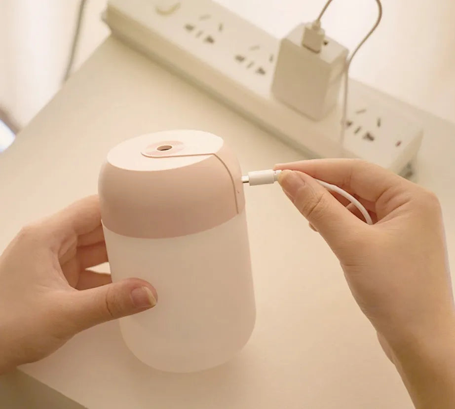 White cylindrical mini humidifier with USB cable on a desk
