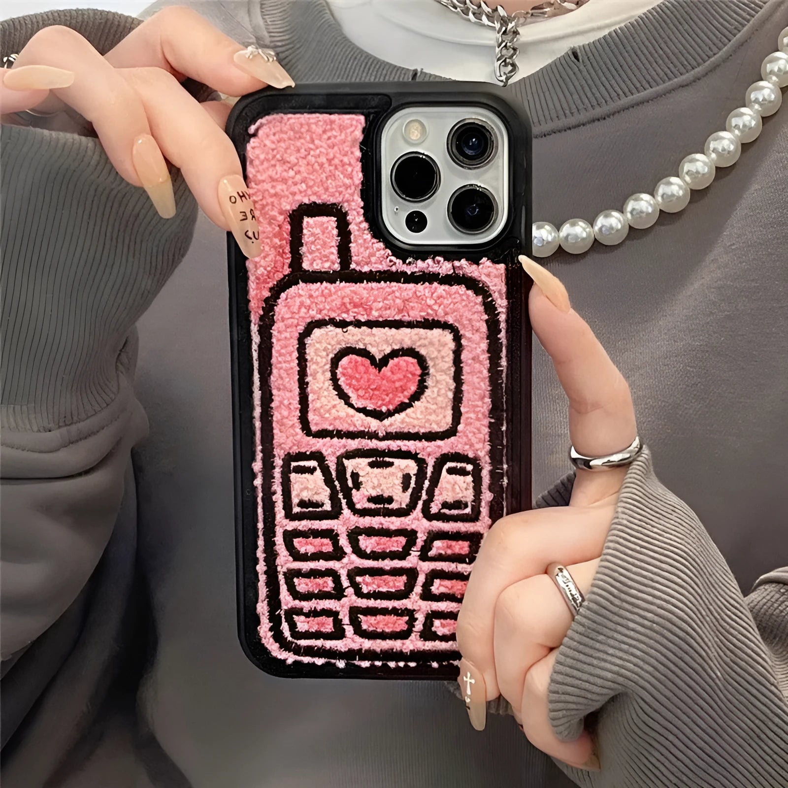 Pink iPhone case with a textured, towel-like embroidered design on the back.
