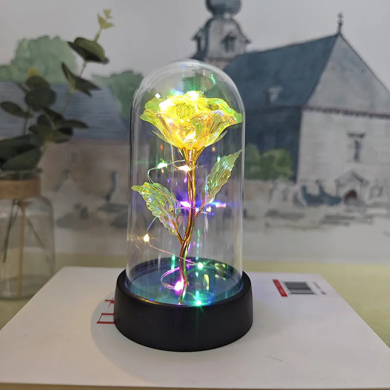 Small decorative night lamp with glass cover and plastic flowers, showing coloured light illumination.