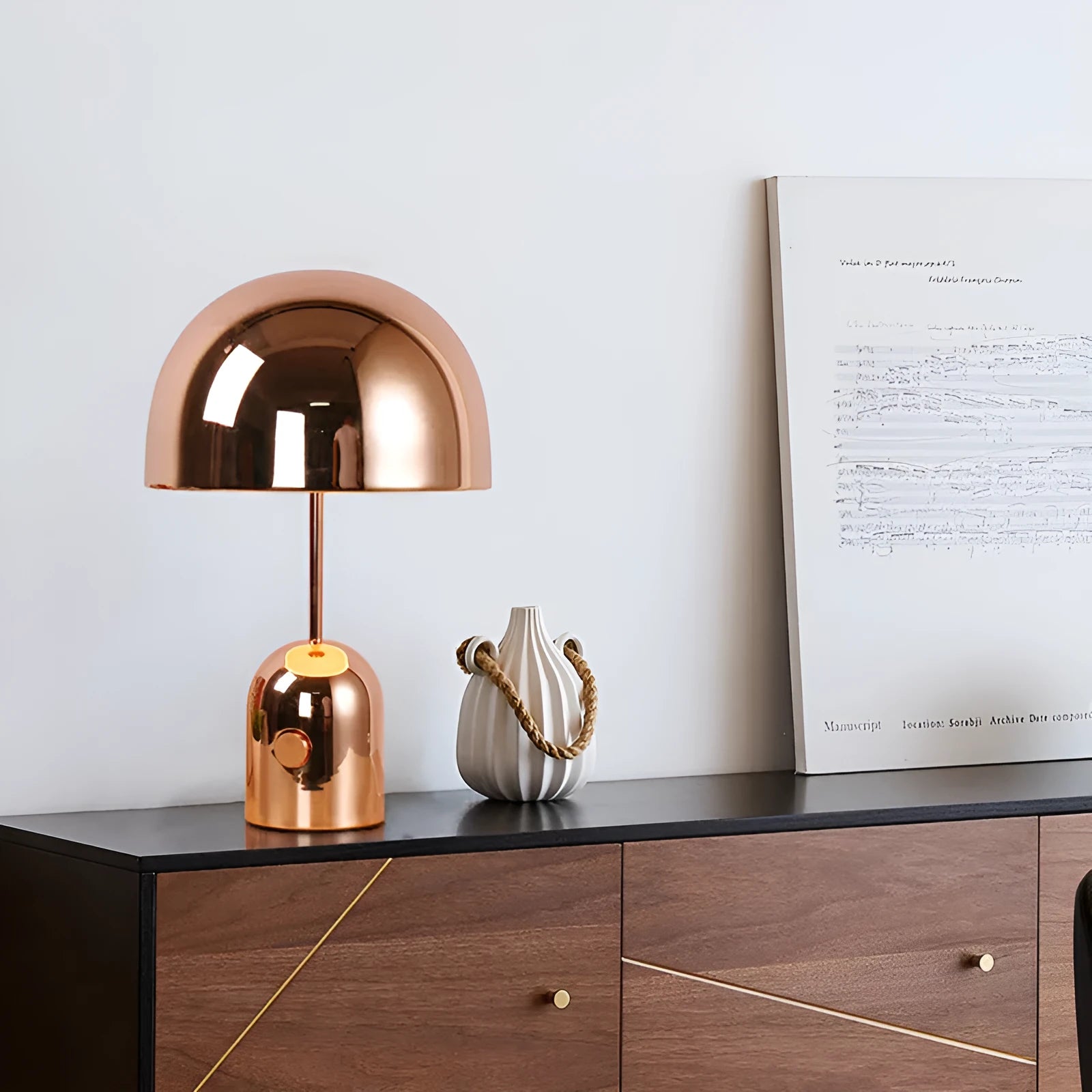 Mushroom-shaped metal table lamp in a rose gold finish on a wooden surface.
