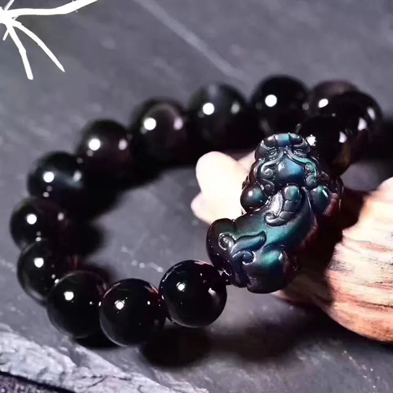 Natural ice colour eye obsidian crystal bracelet on a wrist, showing polished beads on an elasticated band.