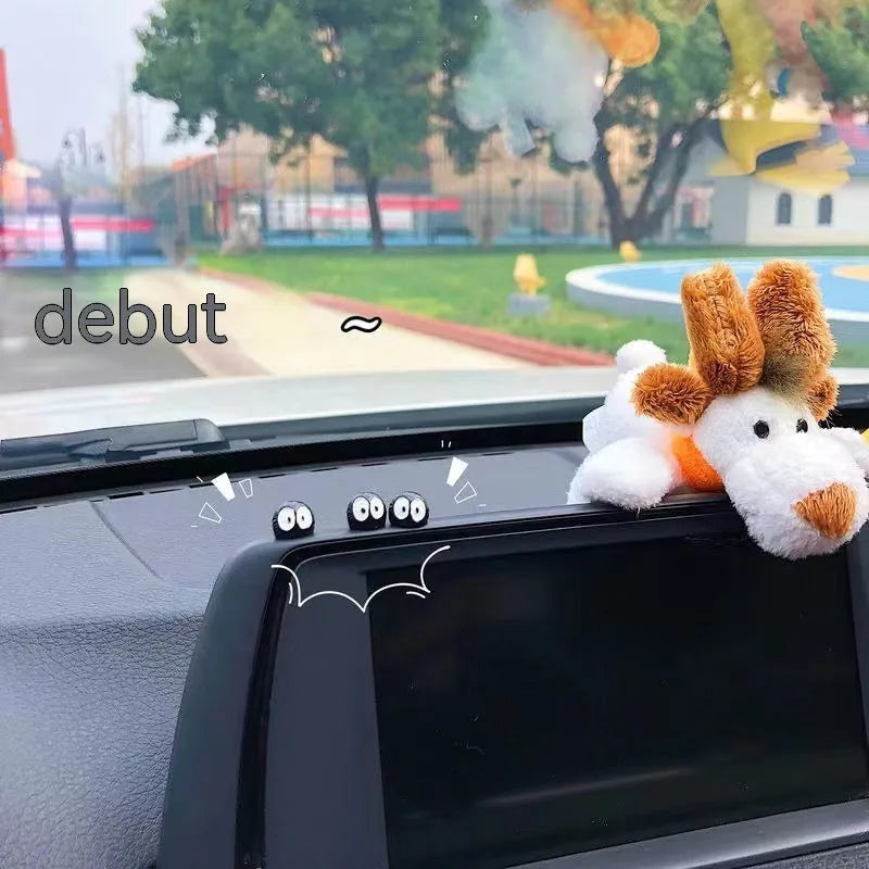 Small black resin coal ball cartoon decoration on a car dashboard.
