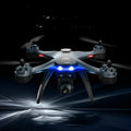 Plastic quadrocopter drone with four rotors, remote controller, spare blades, and protection covers displayed alongside USB cable