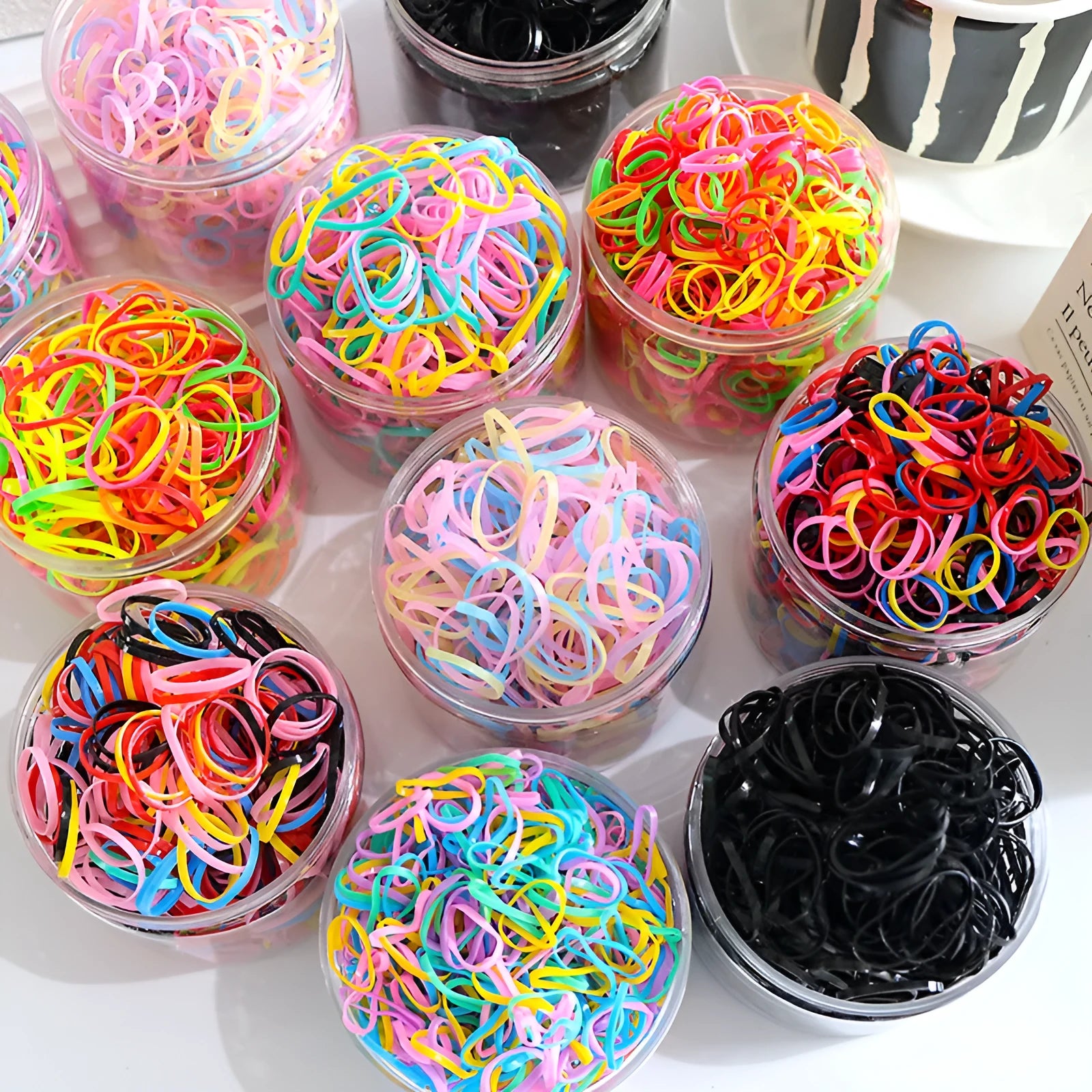Pack of small, colourful TPU elastic hair bands for babies and toddlers in a reusable container.