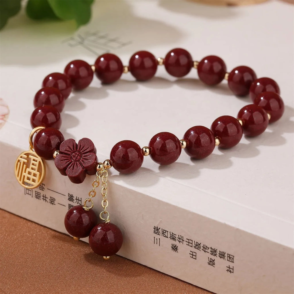 Women's cinnabar bracelet with purple gold sand finish and traditional fu character charm with tassel detailing