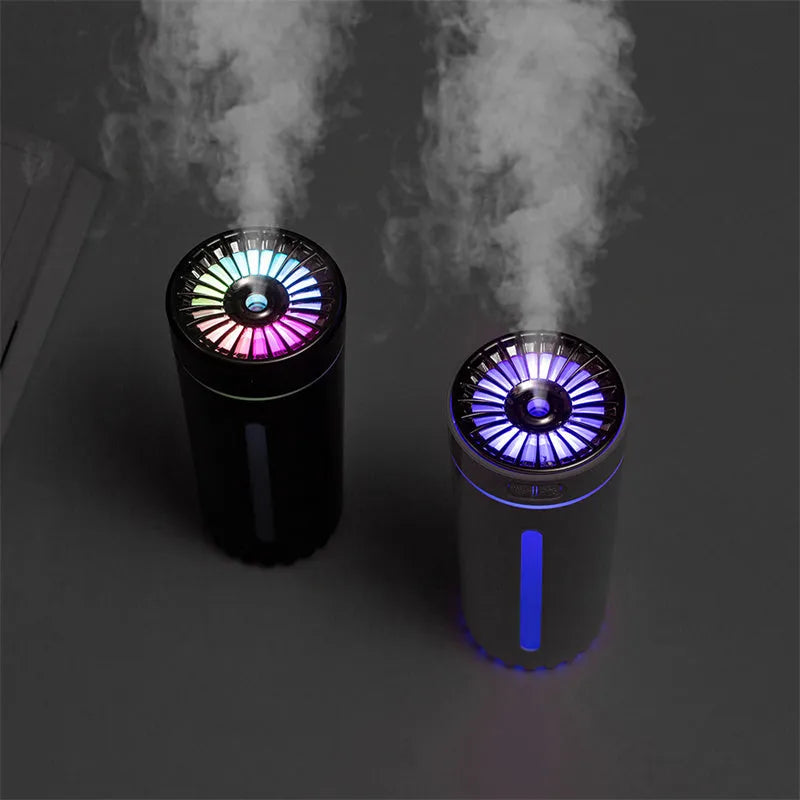 Black wireless ultrasonic humidifier with colourful lights, shown next to a USB cable on a desk.