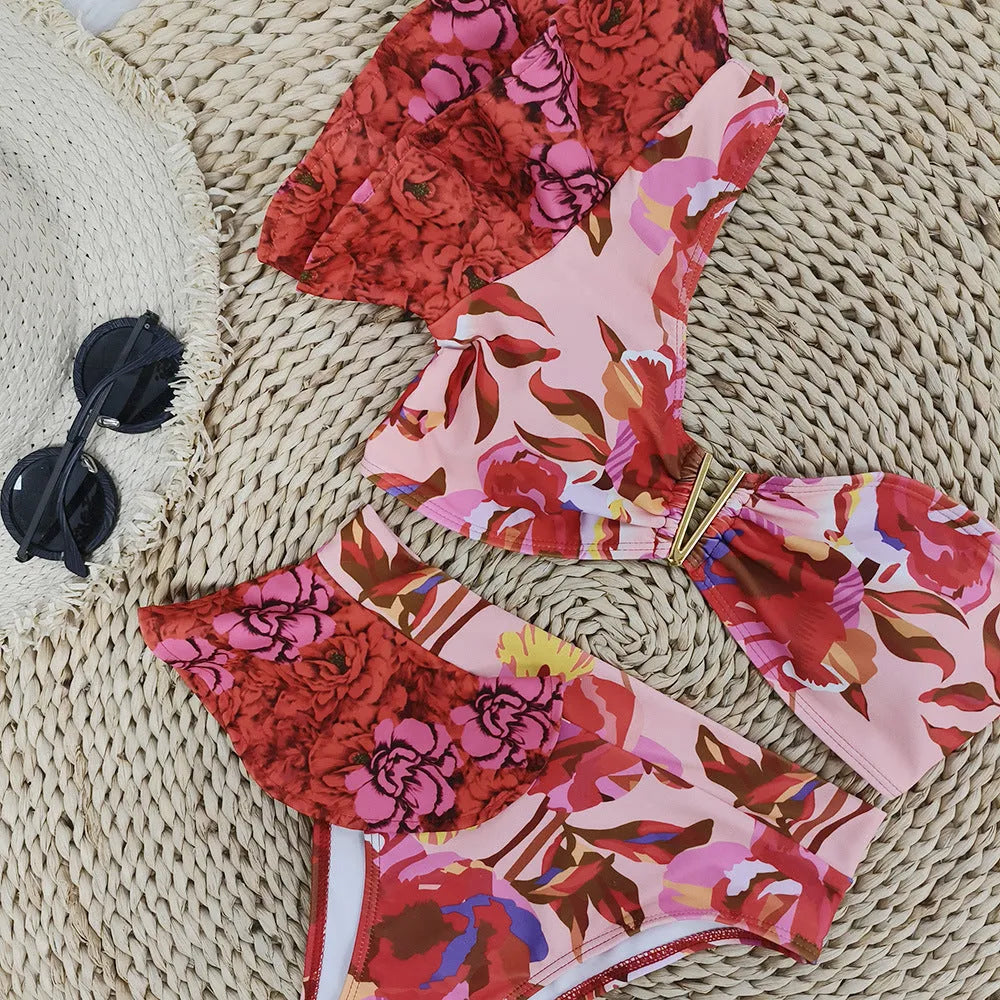 Women's pink floral print one-shoulder ruffled swimsuit with high-waisted bikini briefs.