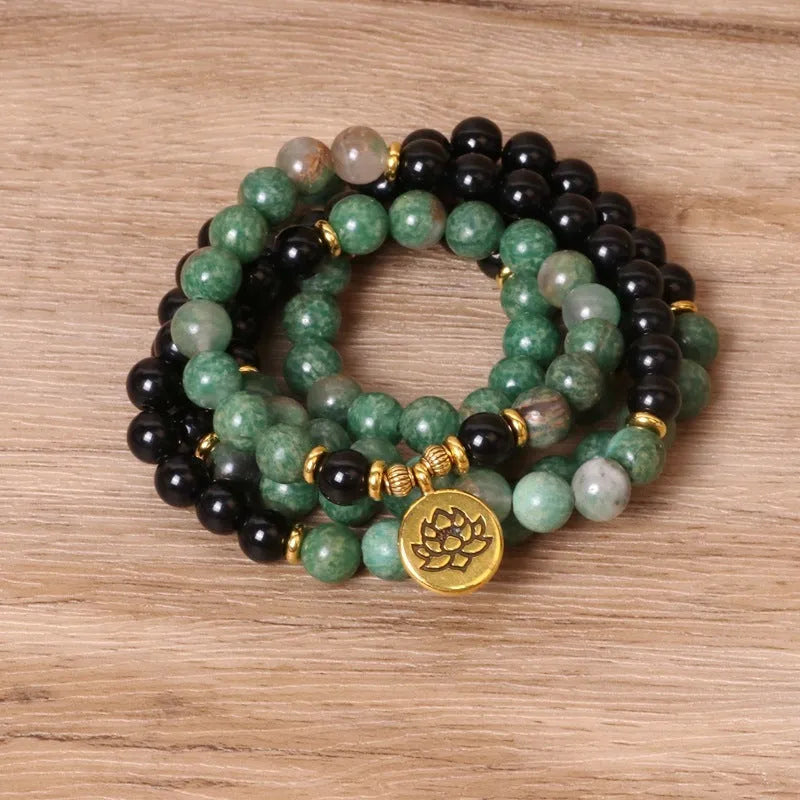 Green and black alloy bead elastic bracelet stretched on a wrist.