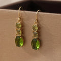 A pair of green square-shaped geometric copper drop earrings on a plain background.