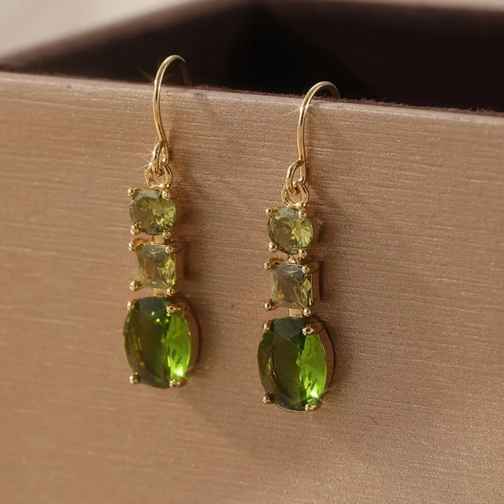 A pair of green square-shaped geometric copper drop earrings on a plain background.