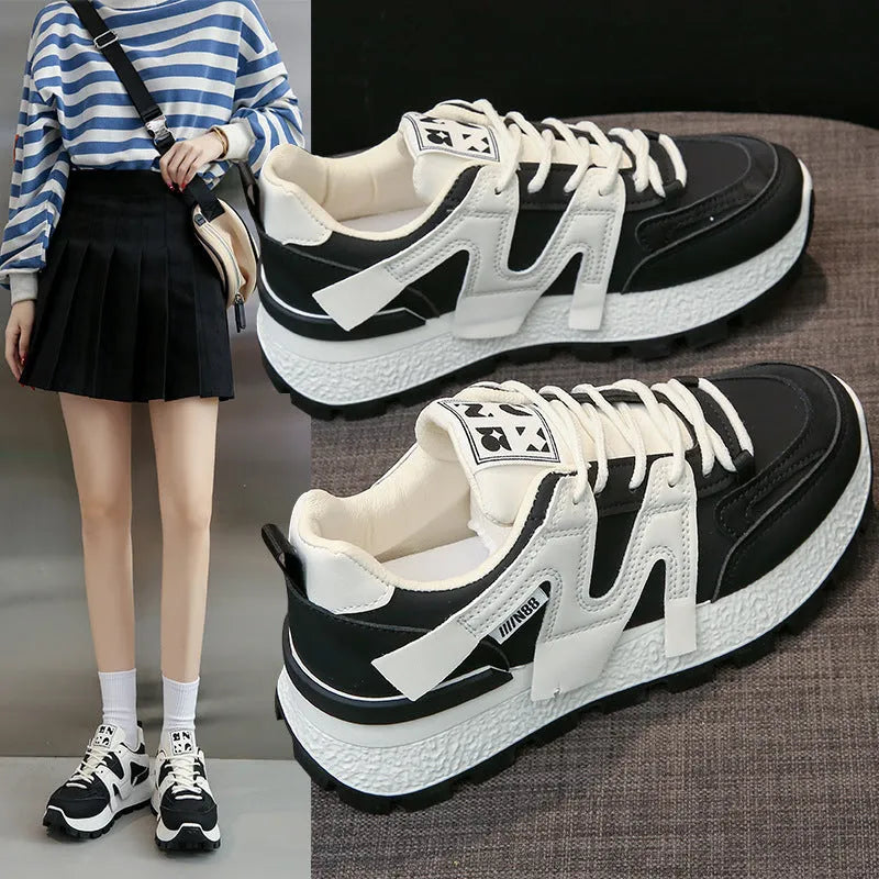 Low-top round-toe sneaker in black or white with lace-up front and flat rubber sole.