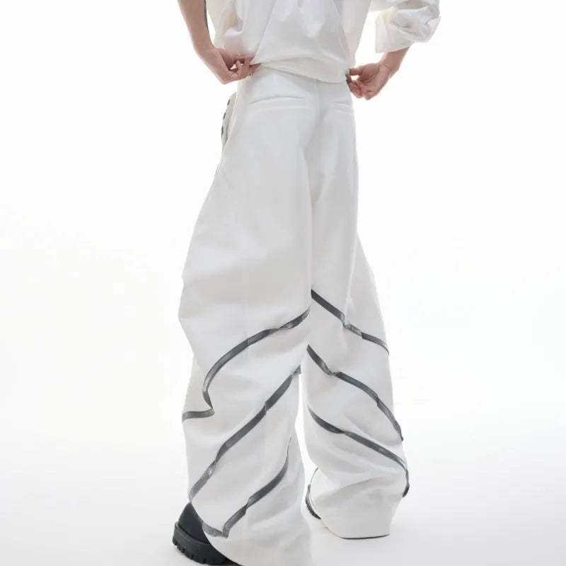 Men's black trousers with structured three-dimensional cut and metal rivet pleats on the legs.