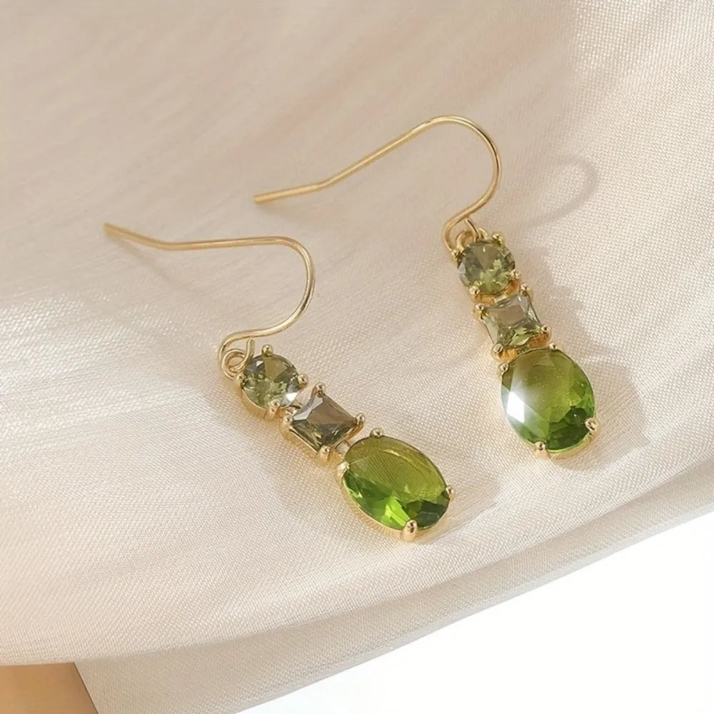 A pair of green square-shaped geometric copper drop earrings on a plain background.