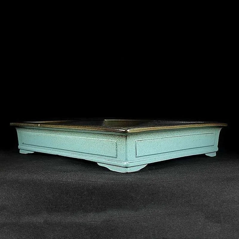 Green handmade ceramic bonsai pot with purple sand crackled glaze on wooden surface