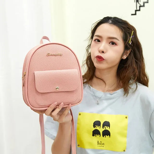 Women's small PU leather backpack shoulder bag in black showing front zipper and compact size