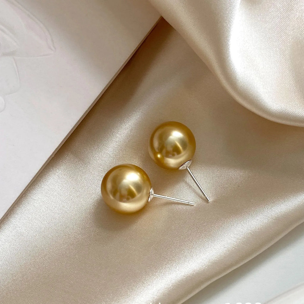 A pair of large pearl stud earrings with a geometric silver setting and an eight-awh star detail on a white background.