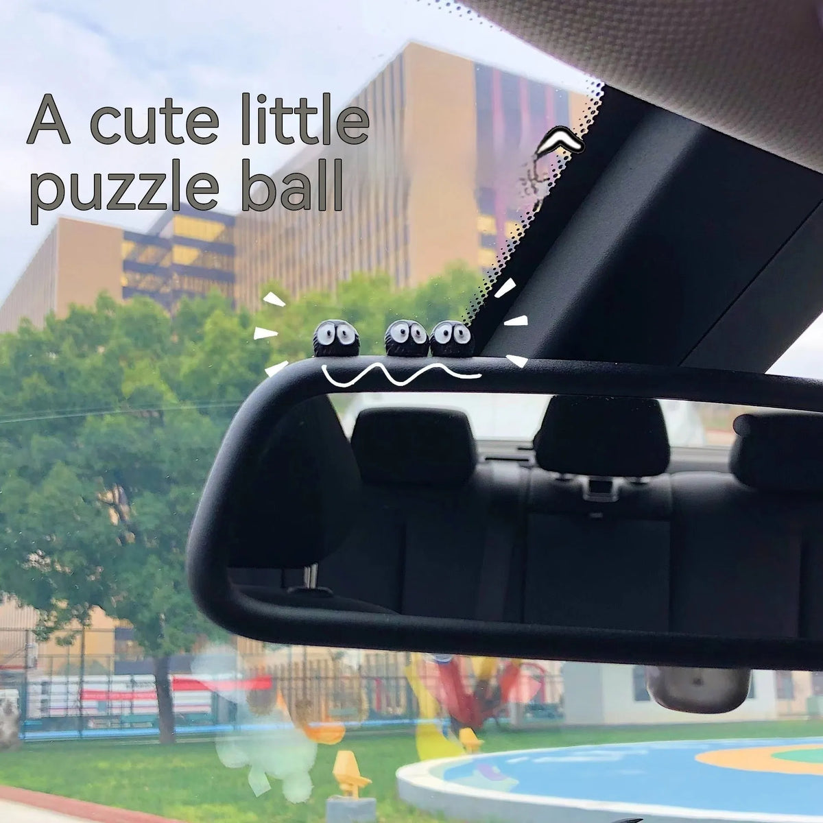 Small black resin coal ball cartoon decoration on a car dashboard.