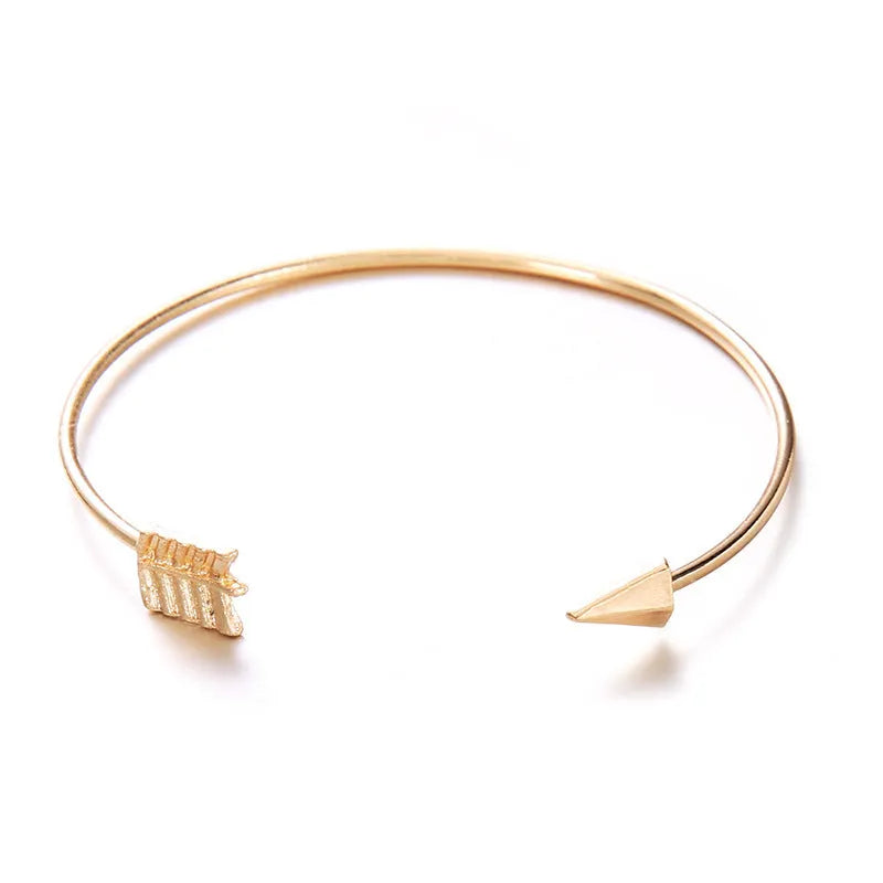 Gold electroplated alloy women's vintage cuff bracelet with knotted arrow design on a white background.