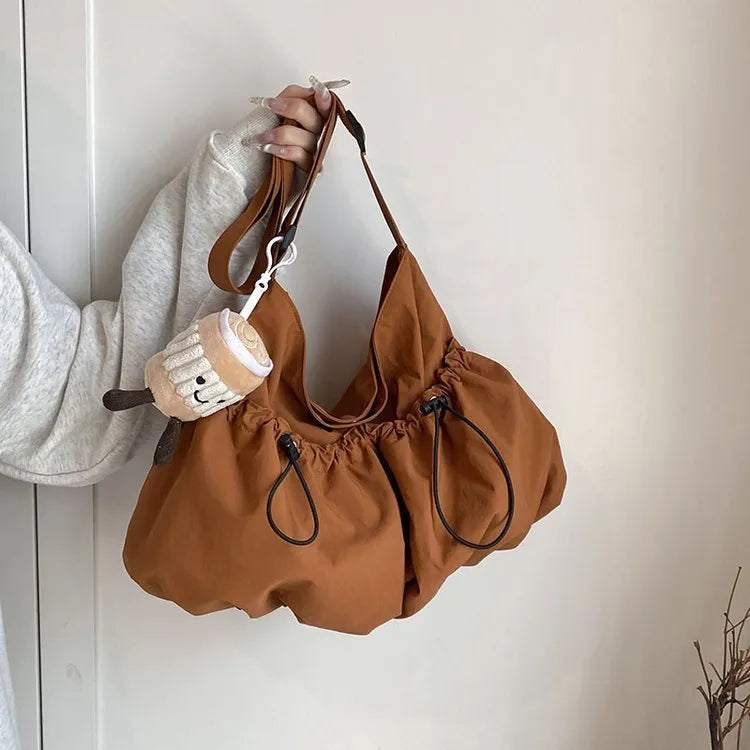 Green pleated folding crossbody student bag with a front split pocket and long strap.