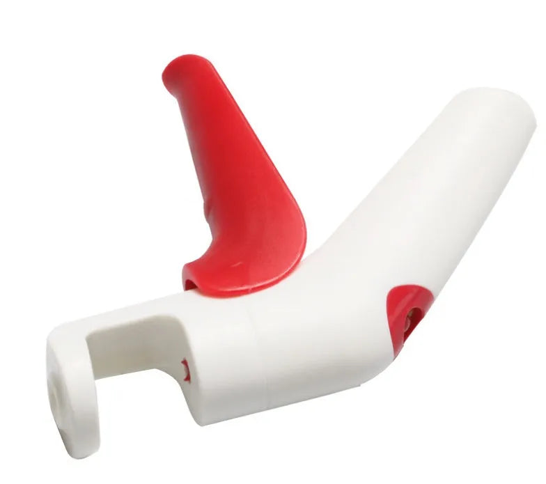 Stainless steel manual cherry kernel remover tool on a kitchen worktop.