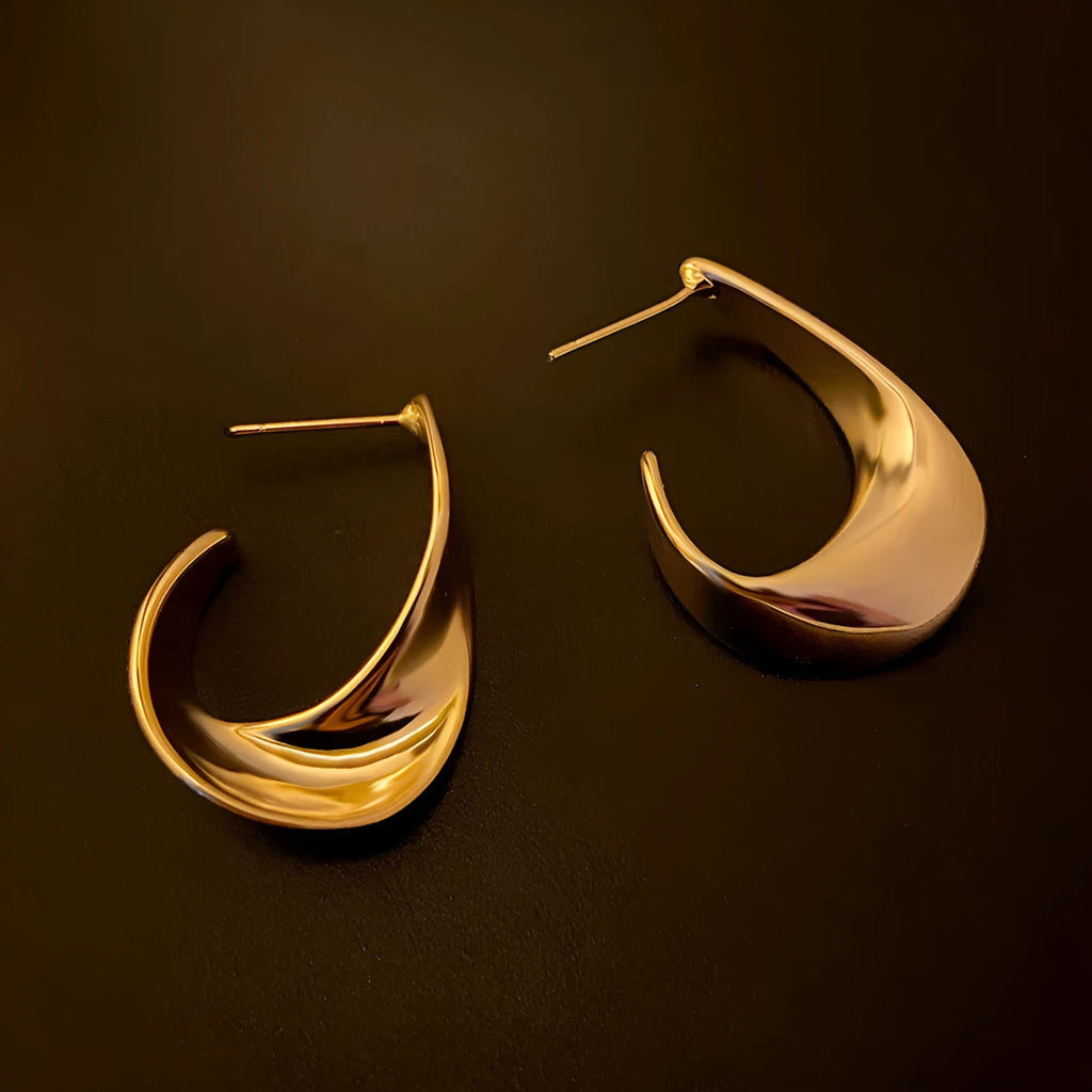 Geometric metal earrings with twisted design and round elements in gold electroplated finish