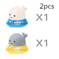 Whale-shaped electric bath toy spraying water with coloured LED lights, shown with base unit on blue background