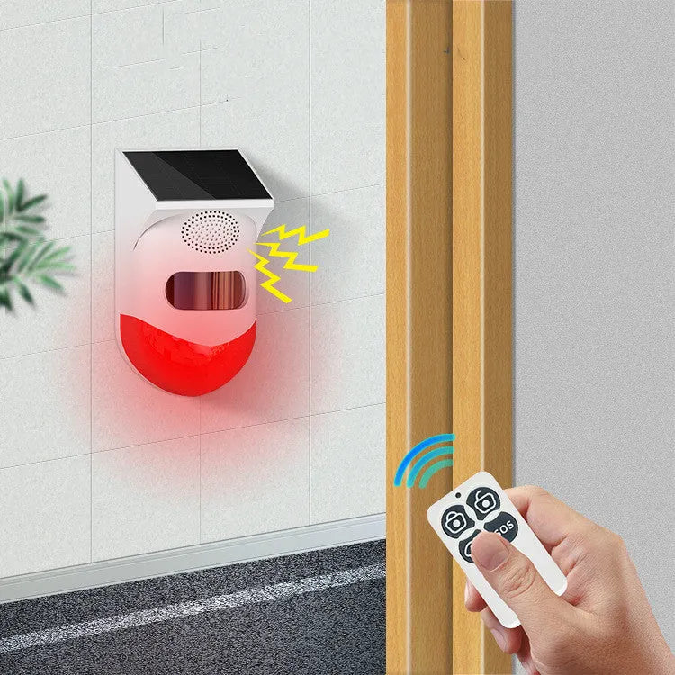 Solar panel human body infrared sensing security alarm with remote control on a wall.