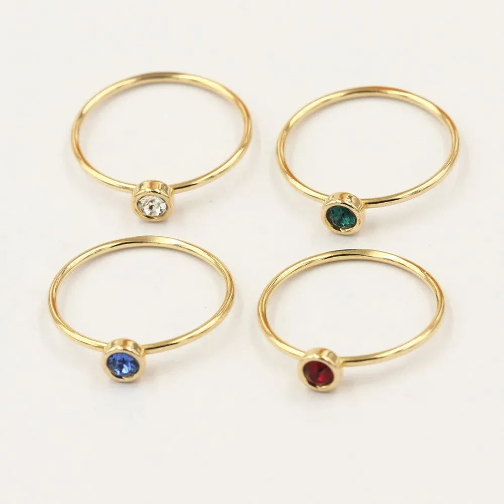 Women's copper knuckle ring with gilded finish and zircon stones in green, blue, red, and white.