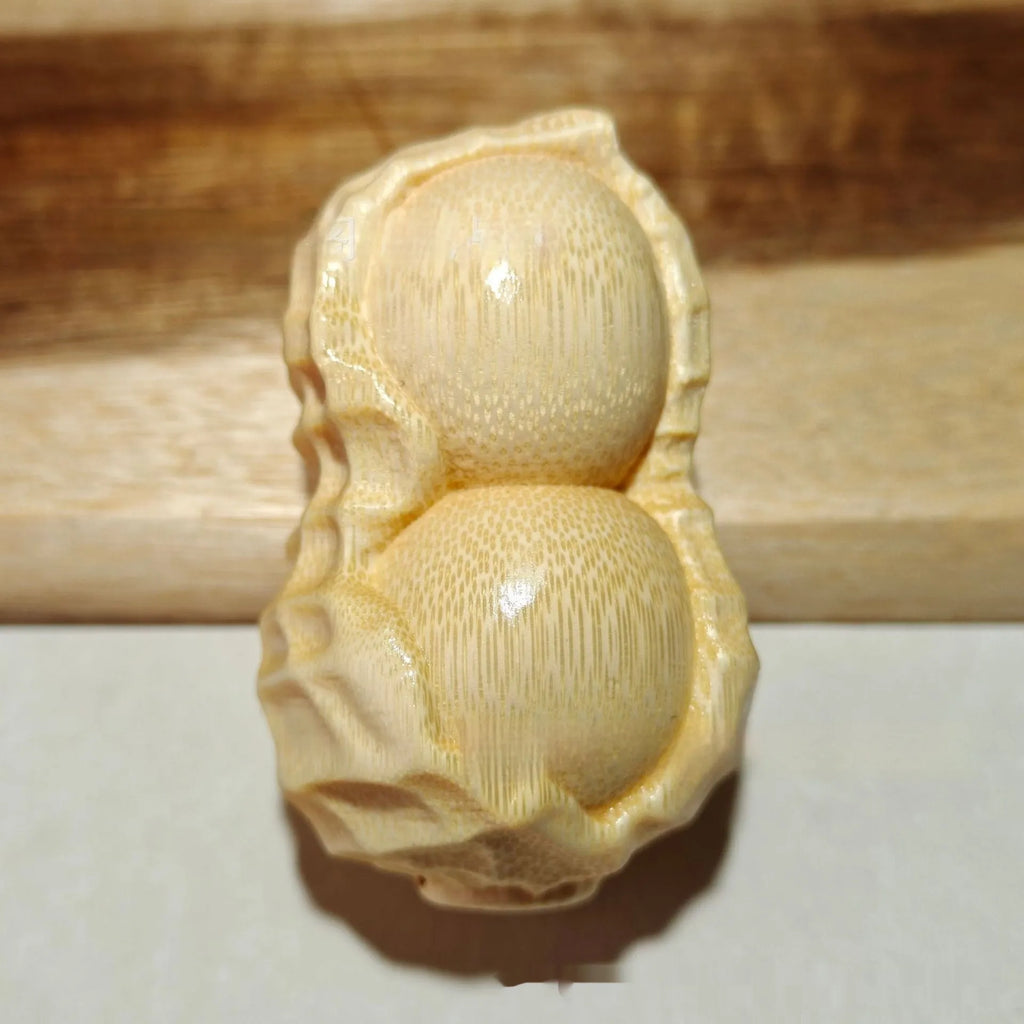 Solid bamboo peanut-shaped ornament with natural wood grain on wooden surface