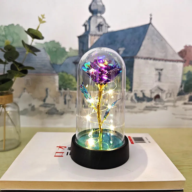 Small decorative night lamp with glass cover and plastic flowers, showing coloured light illumination.