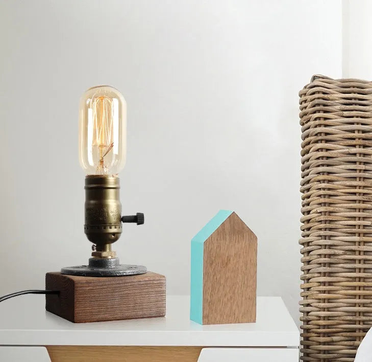 Compact wooden and iron water pipe table lamp on a table surface