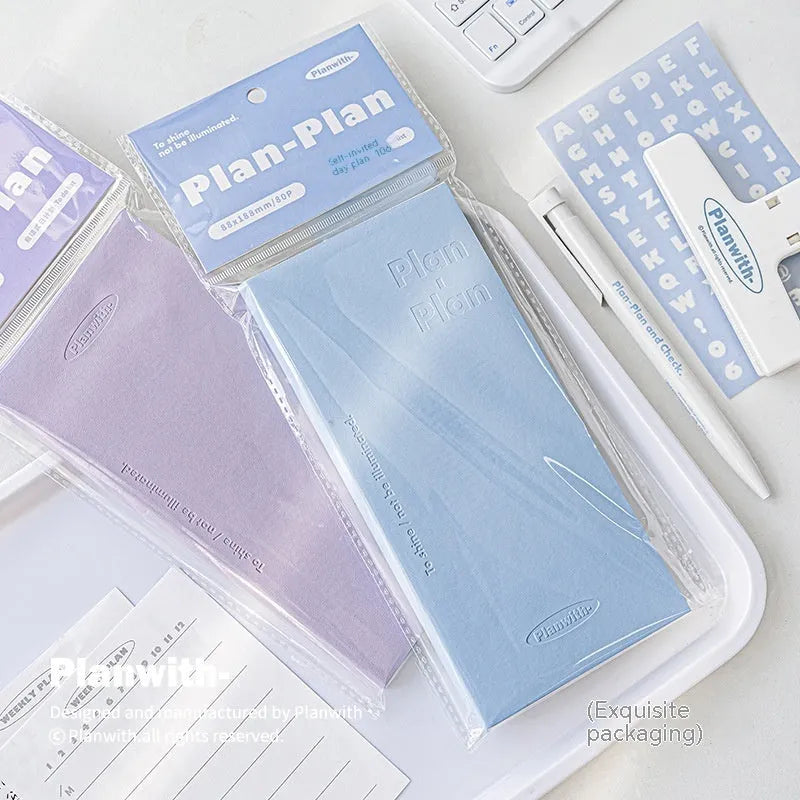 A5 embossed meter notebook open on a desk, showing white 100gsm paper and a choice of five cover colours.