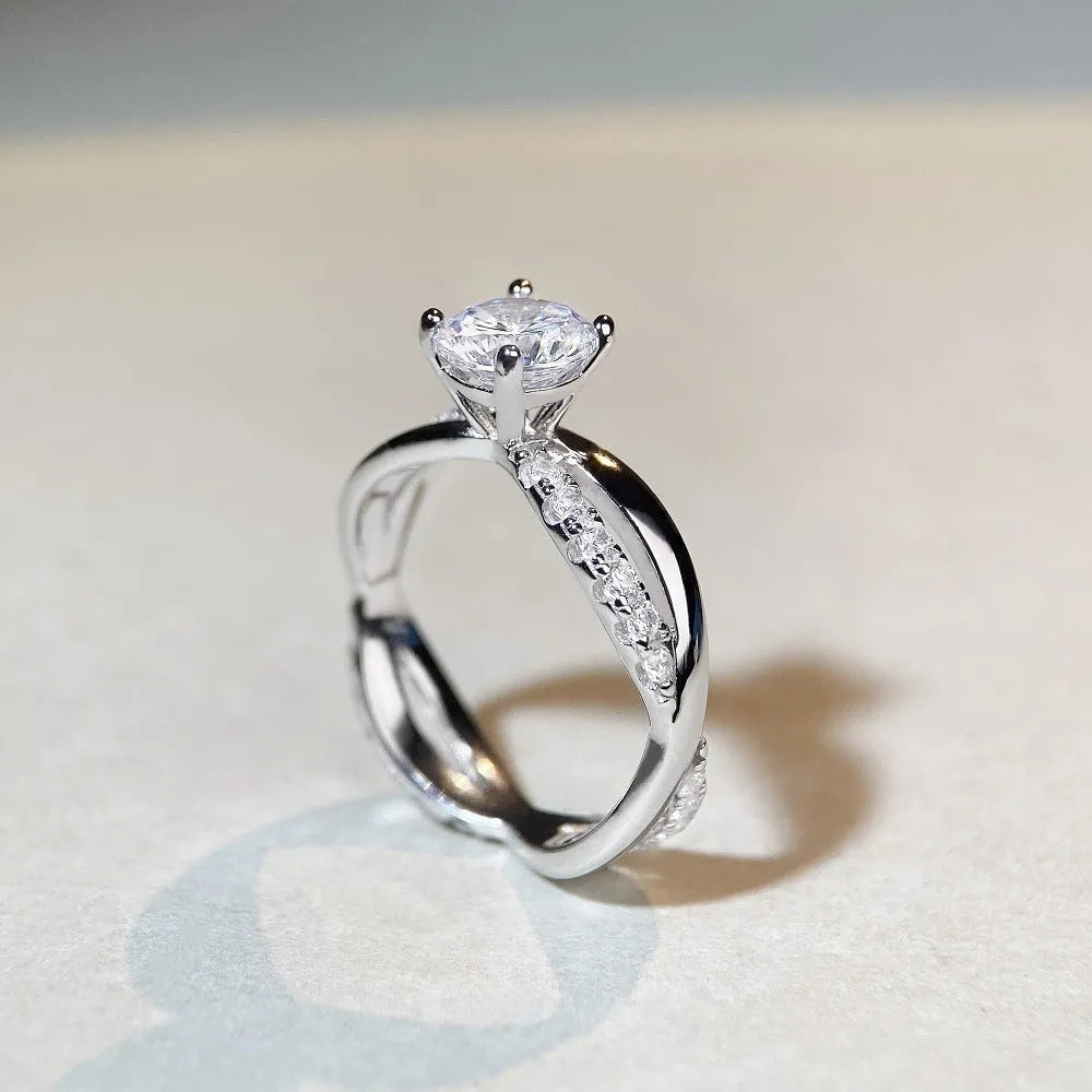 Women's geometric cross moissanite ring with twisted silver band and 1 carat stone.