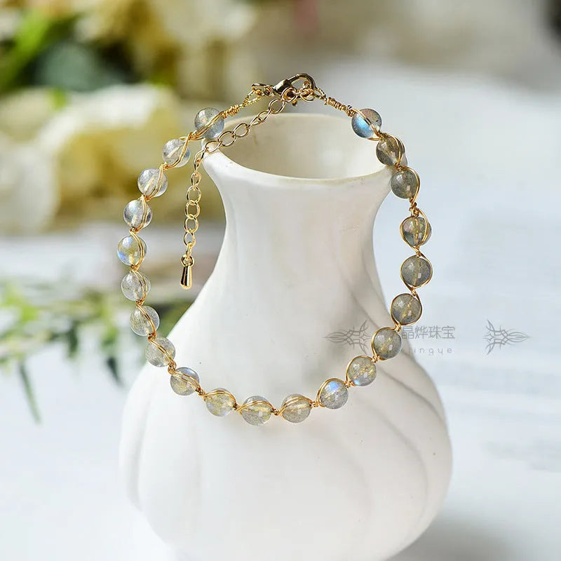 Blue moonstone and gold tone bracelet with 6mm beads on a wrist.