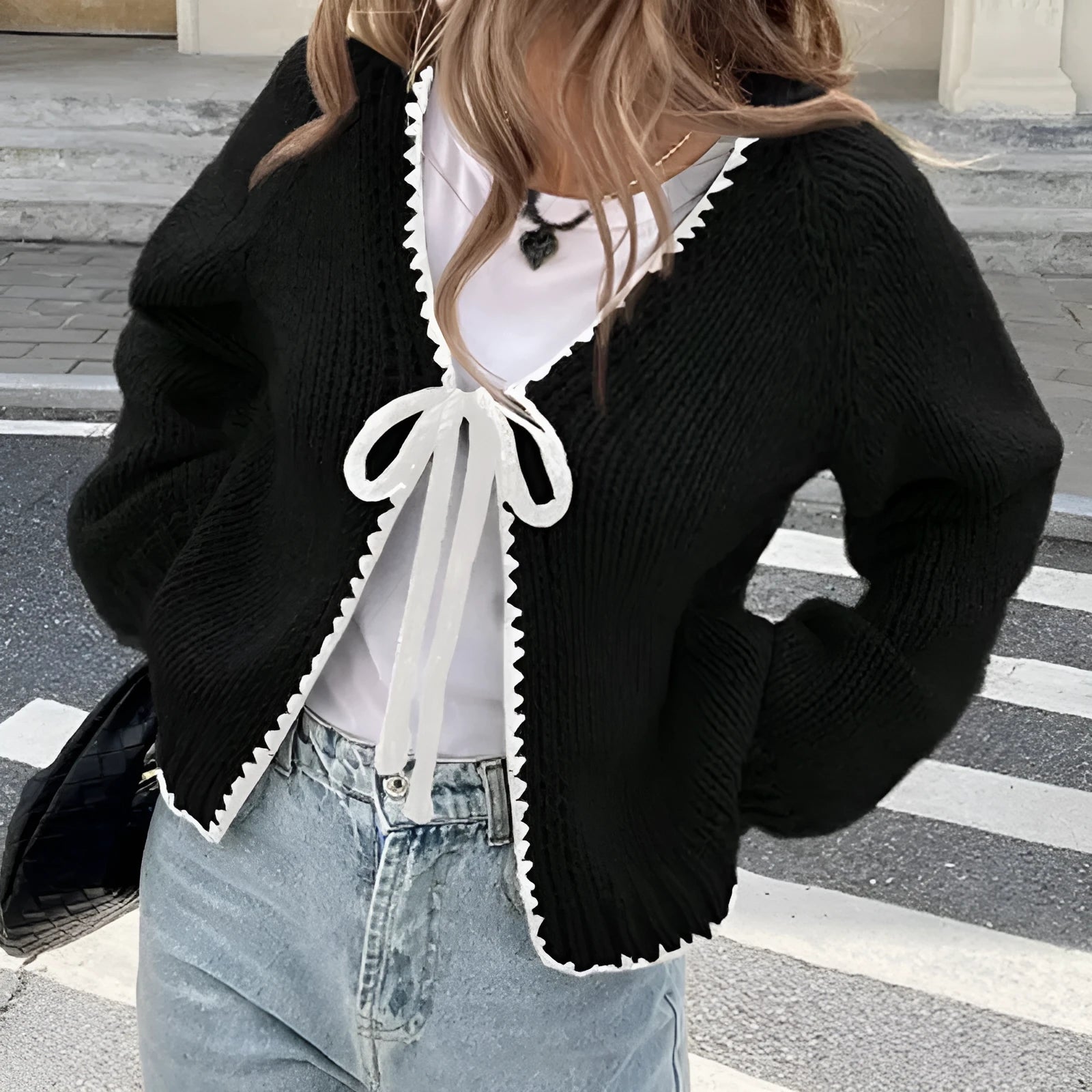 Gray lace-up front cardigan with crocheted flower detail on a model, showing loose long sleeves.