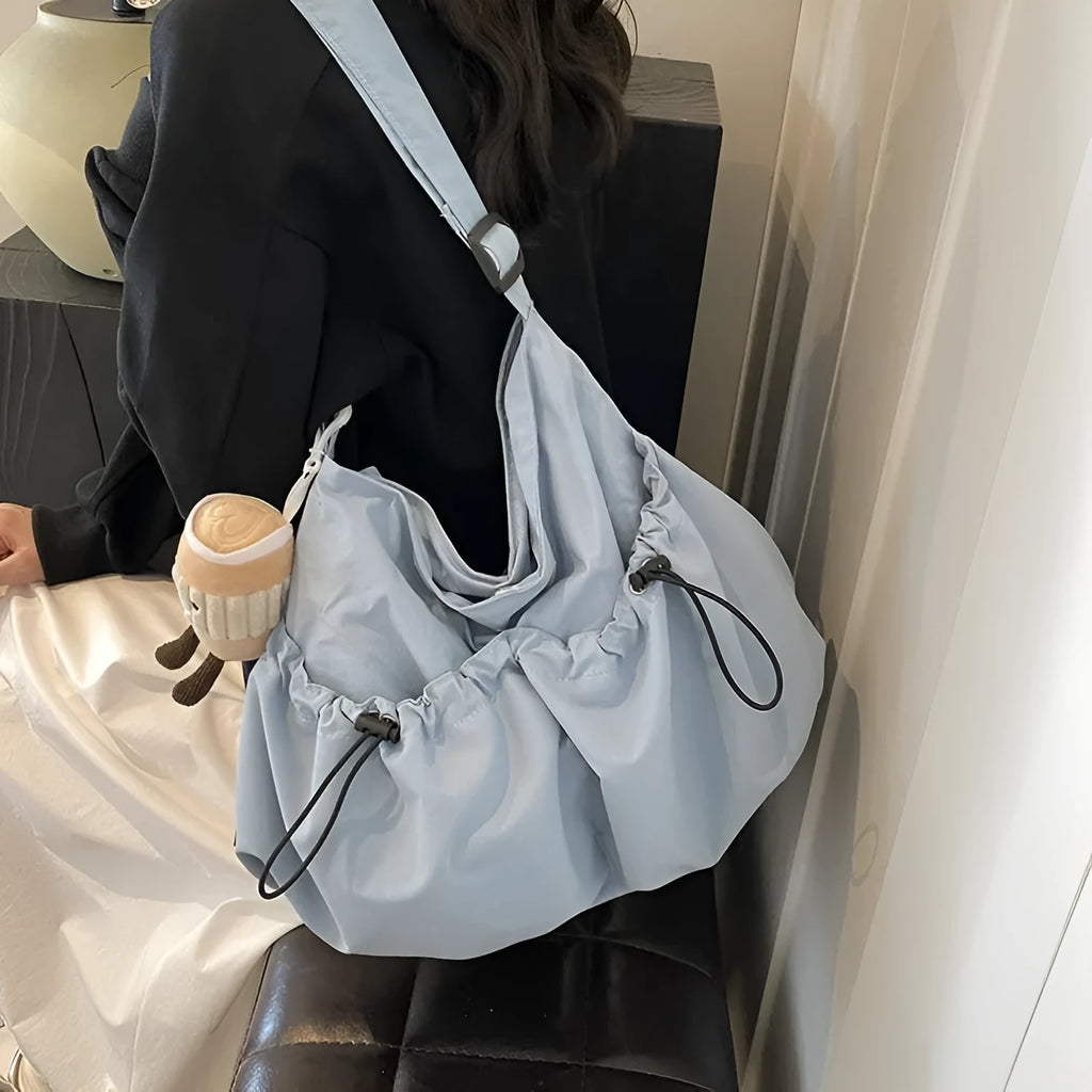 Green pleated folding crossbody student bag with a front split pocket and long strap.