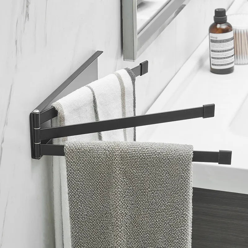 Black folding towel rack mounted on a bathroom wall with towels hanging, showing its no-drill installation.