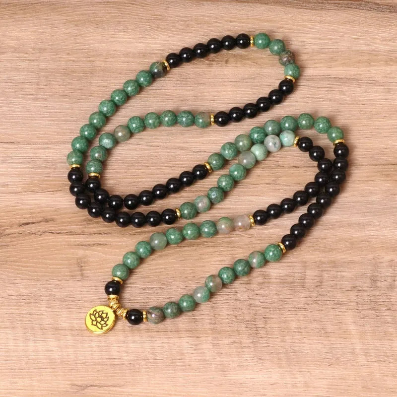 Green and black alloy bead elastic bracelet stretched on a wrist.