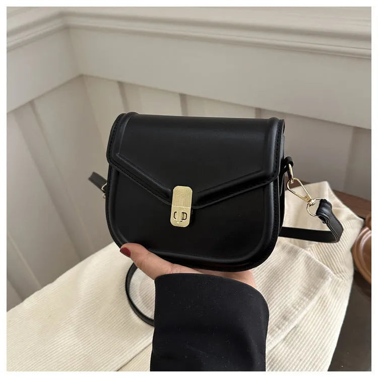 Men's soft black PU leather clamshell messenger bag in a horizontal square shape on a table.