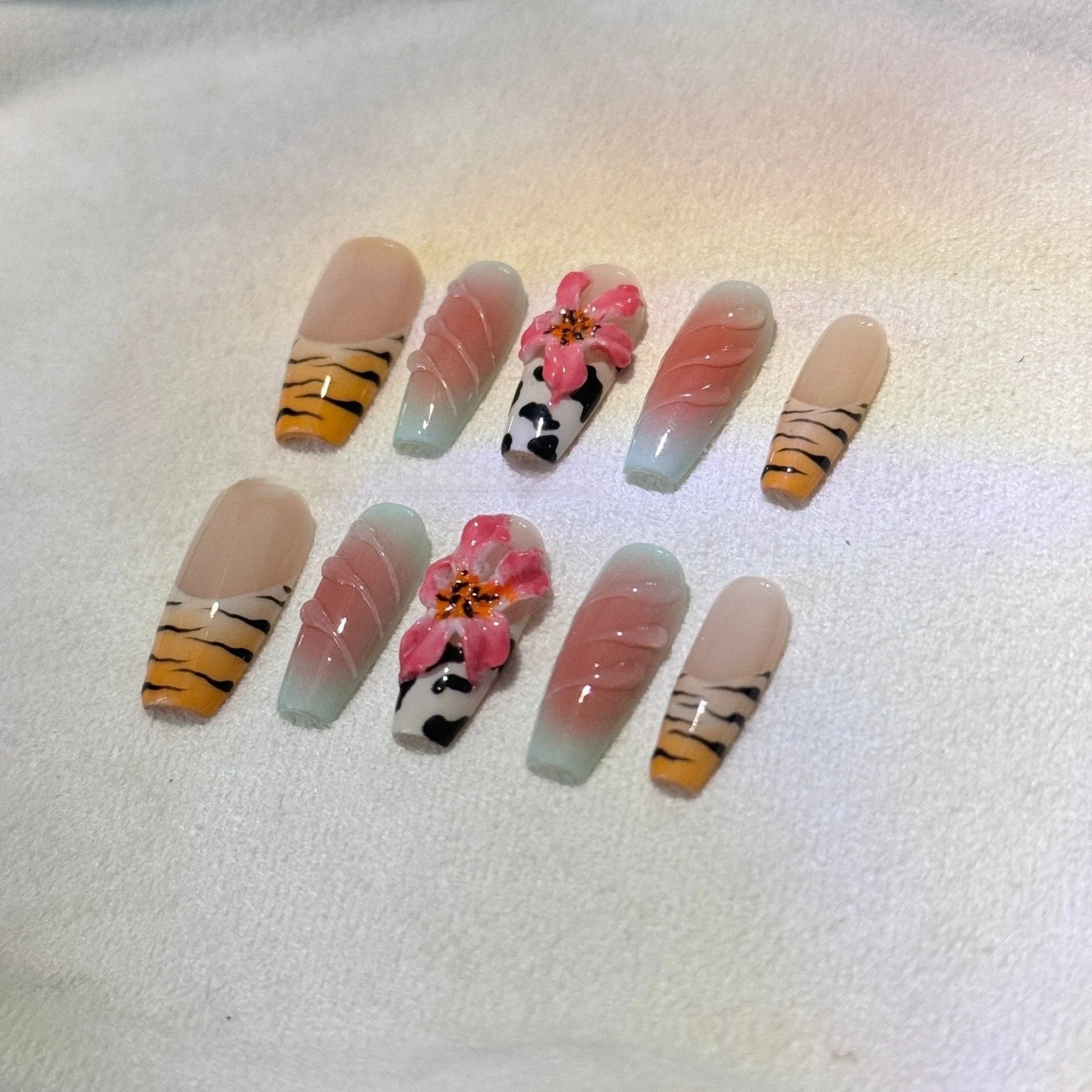 Hand-carved zebra pattern and lily design nail art pieces in four sizes on a clear background.