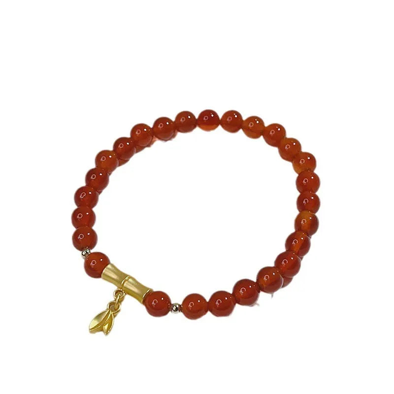 Close-up of a manually crafted red agate bracelet with Lucky Bag and dragon designs on a wrist.