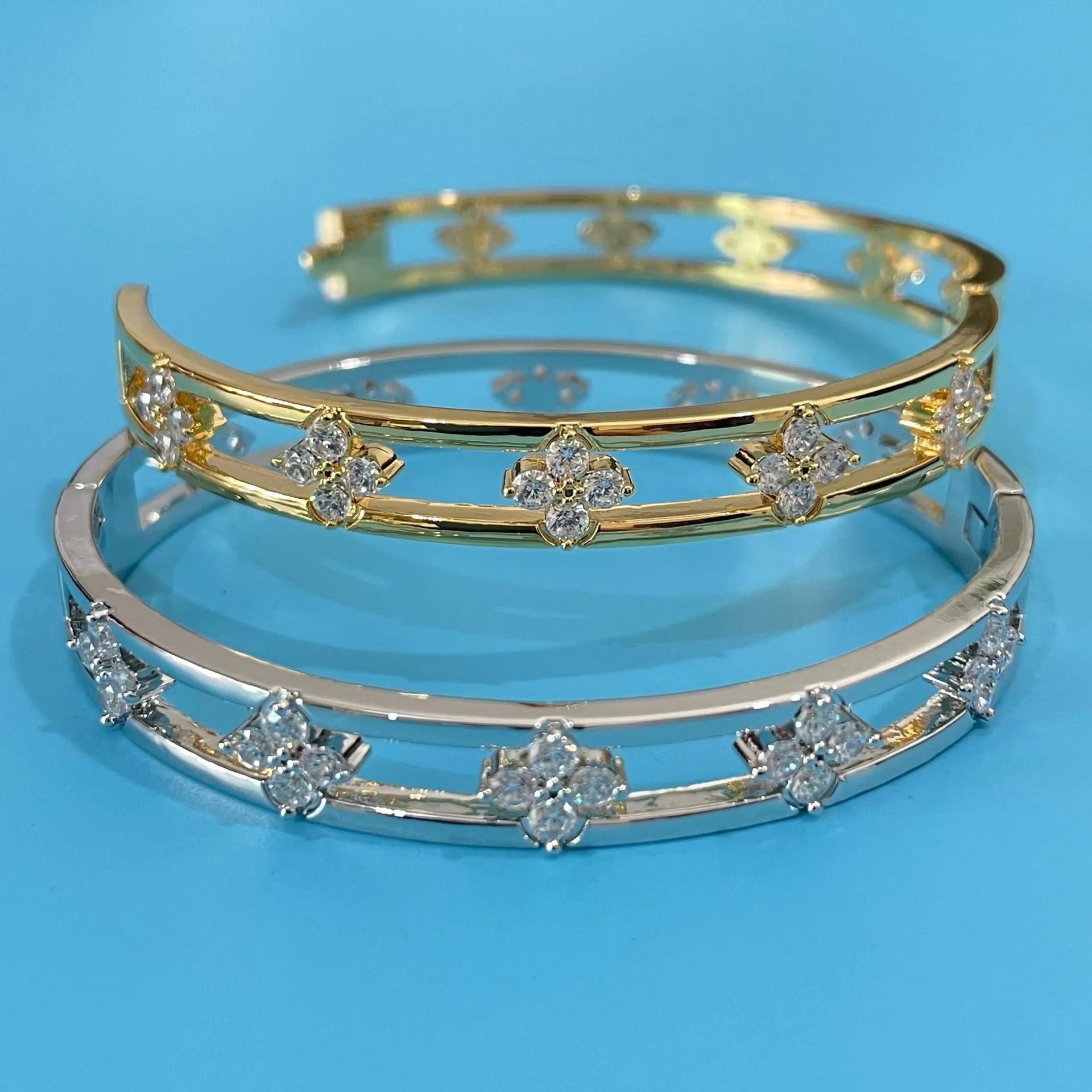 Women's hollow bracelet with a four-leaf clover zircon charm on an adjustable band, shown in gold and silver finishes.
