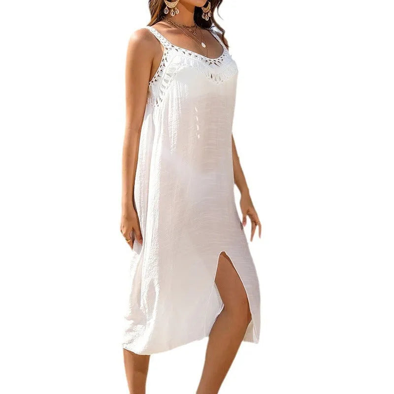 White suspender beach dress with hollow crochet weaving and a bottom slit, laid flat.