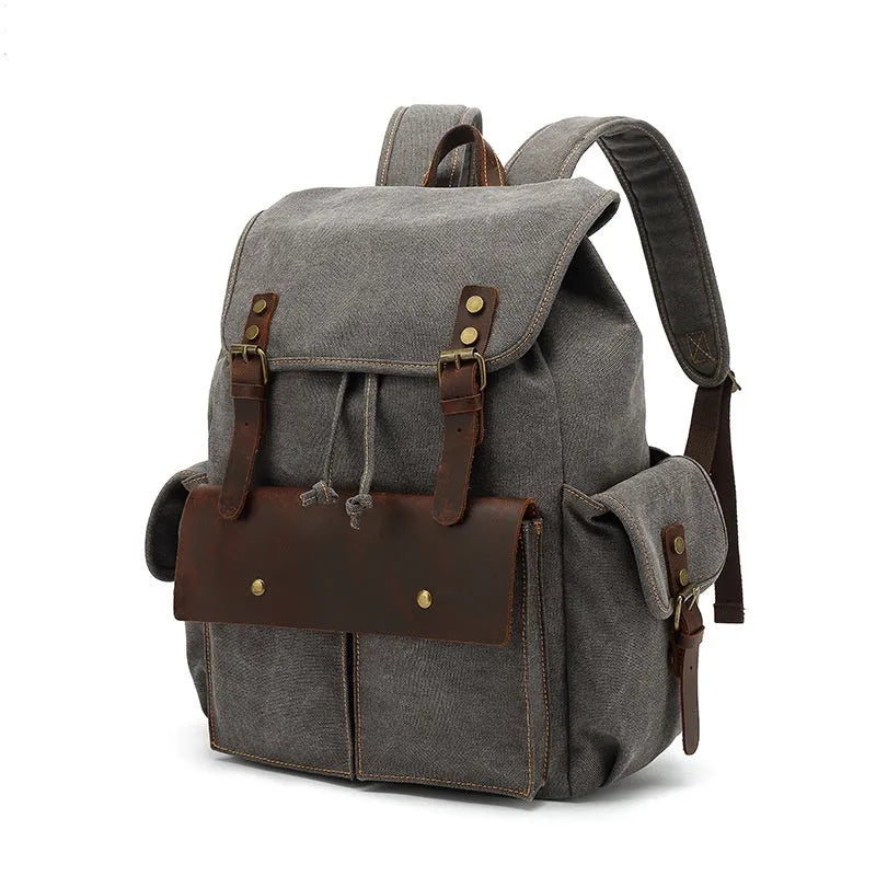Retro canvas backpack in army green colour with antique bronze hardware, shown with a laptop to scale.