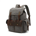 Retro canvas backpack in army green colour with antique bronze hardware, shown with a laptop to scale.