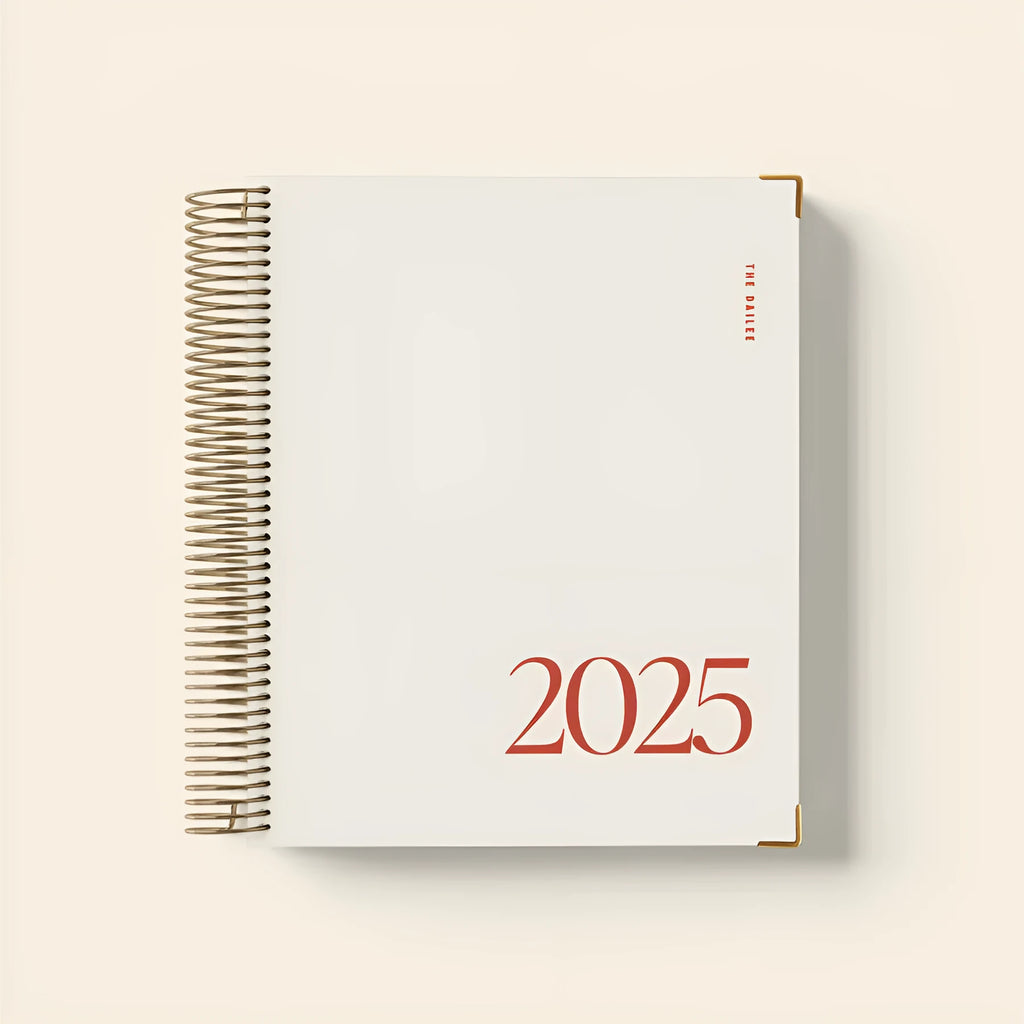 Cherry red coil-bound daily schedule notebook with spiral binding open on a desk