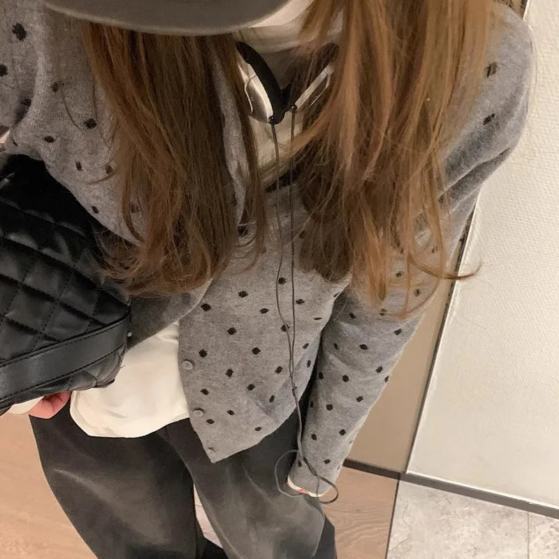 Women's grey dot patterned knitted cardigan with crochet flower detail on sleeve.
