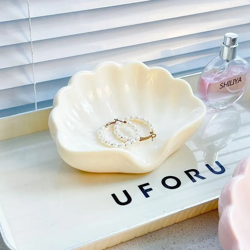 White plastic shell-shaped soap dish for bathroom countertop or wall.